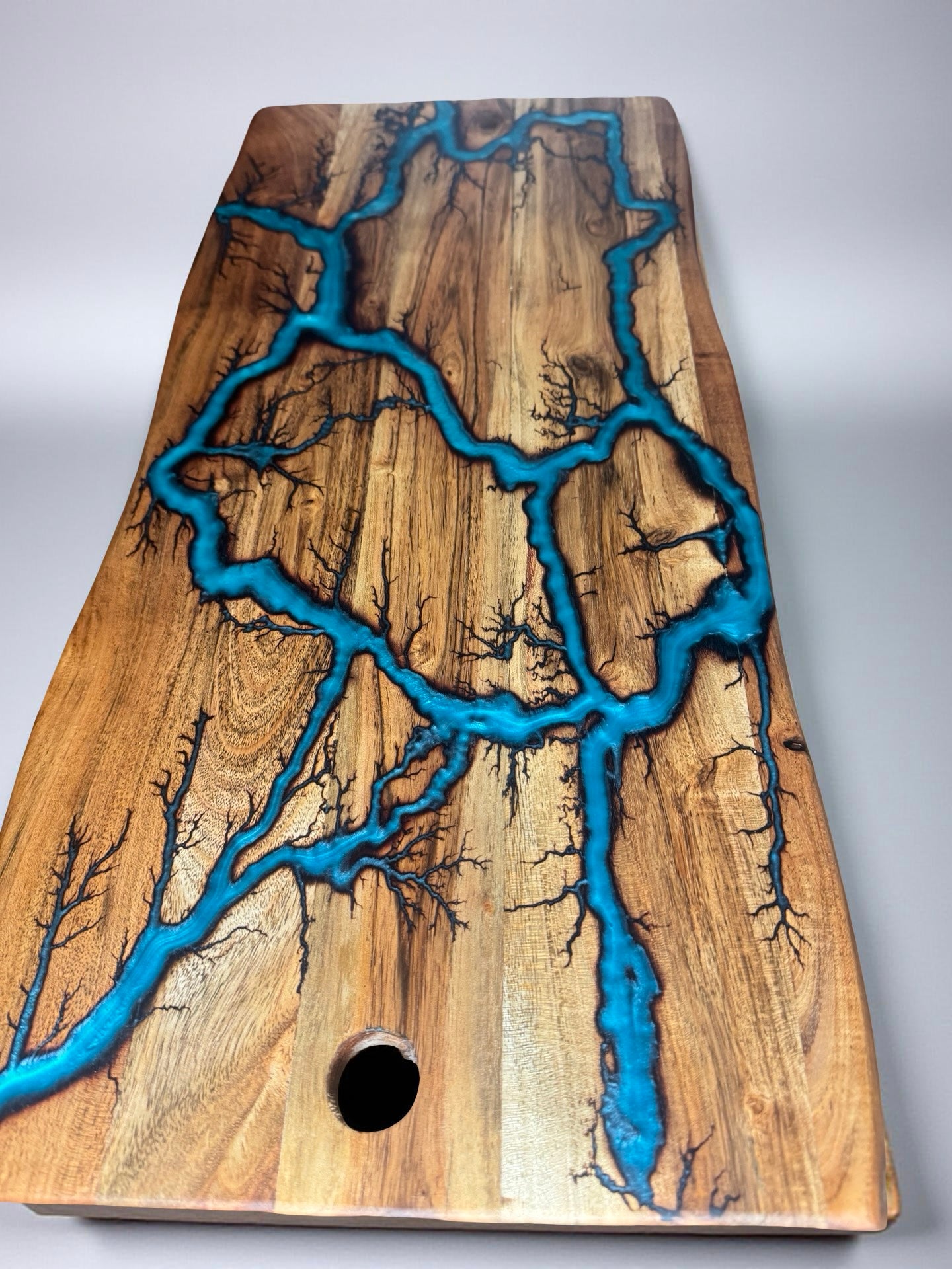 live edge serving board mae by fractal flo designs featuring lagoon blue resin in a fractal burning patern made by fractal flow designs measuring 570mmx280mmx20mm
