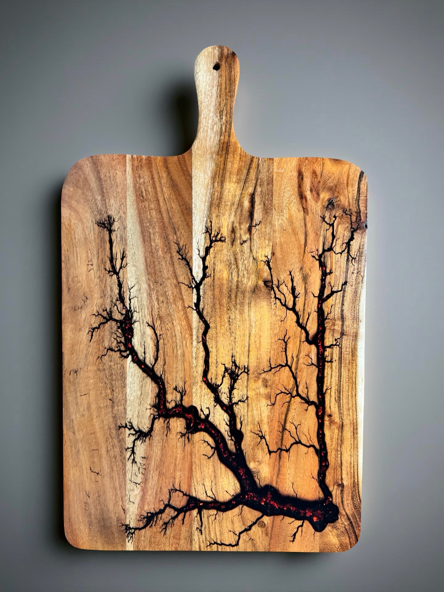 Grazing paddle board with vibrant red flash resin pour and electric burnt timber grain accents